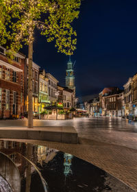 Bridge over canal by buildings in city at night