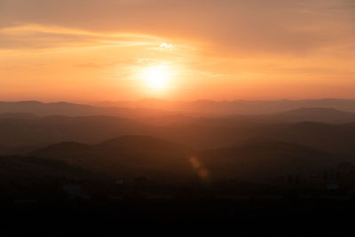 Scenic view of silhouette mountains against orange sky