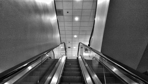 Low angle view of escalator against tiled ceiling