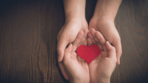 Midsection of woman holding heart shape on hand