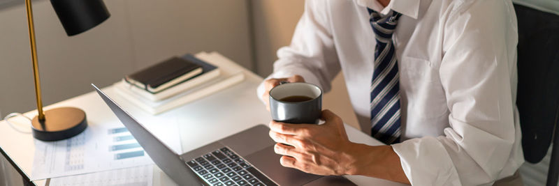 Midsection of businessman holding coffee cup