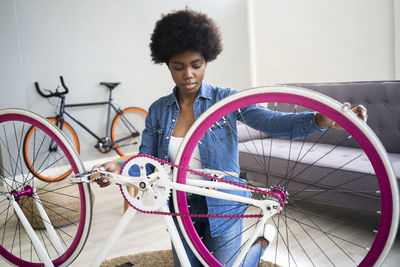 Afro hairstyle woman repairing bicycle at home