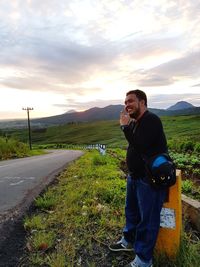 Man photographing while standing on camera against sky