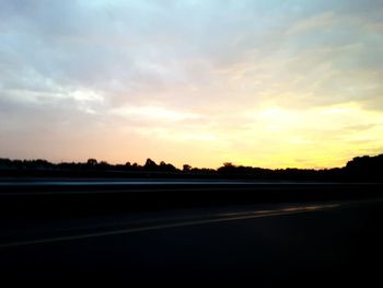 Road by silhouette landscape against sky during sunset