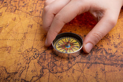 Close-up of hand holding navigational compass on map