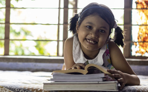 Portrait of smiling girl with book on table