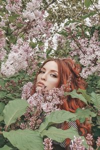 Portrait of woman with pink flower against trees