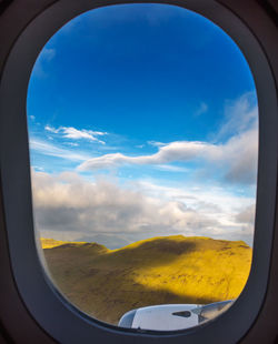 Scenic view of landscape against sky seen through airplane window