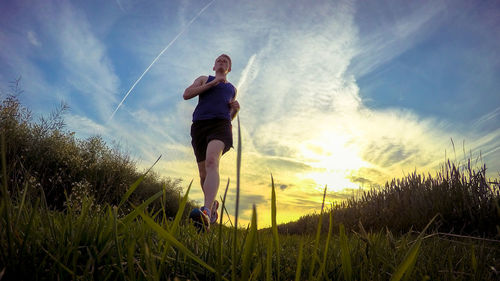 Full length of man exercising on field during sunset