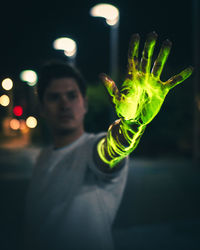 Portrait of young man holding leaf at night