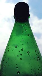 Close-up of wet glass bottle against sky