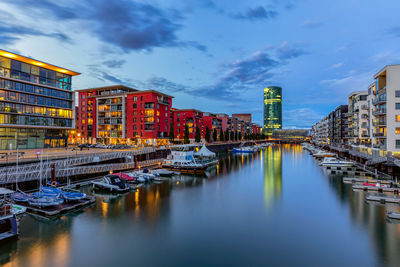 Boats moored in river by buildings in city against sky