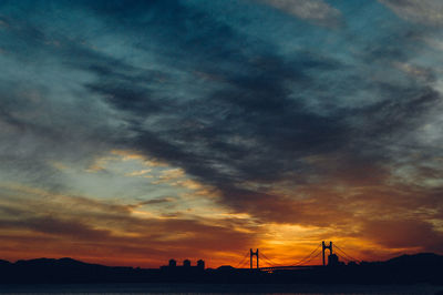 Silhouette bridge against cloudy sky during sunset