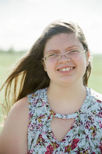 Portrait of overweight teenage girl wearing eyeglasses smiling on field during sunny day