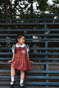 Schoolgirl looking away while sitting on bench