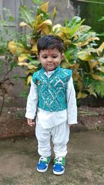 Portrait of boy standing against plants