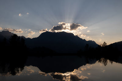 Silhouette trees by lake against sky during sunset