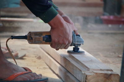 Low section of man working on wood in workshop