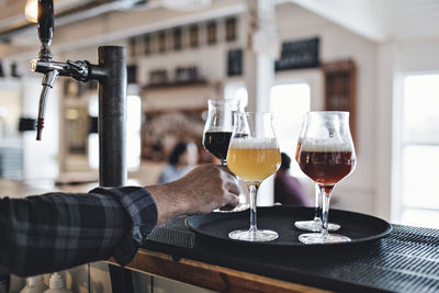 Cropped image of bartender keeping beer glass on tray at counter