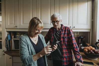 Senior couple using smart phone at home