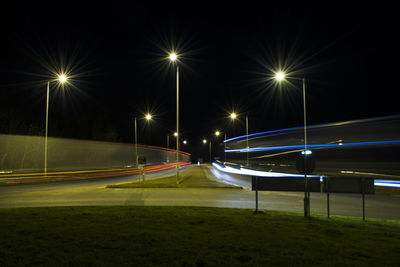 Light trails on street against sky at night