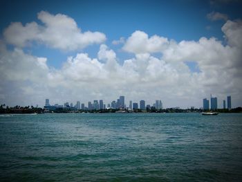 Sea by cityscape against sky