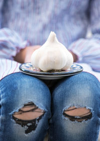 Midsection of woman holding garlic in plate