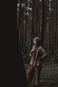 Young woman wearing hijab while standing in forest