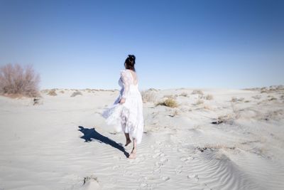 Rear view of woman on rock against sky