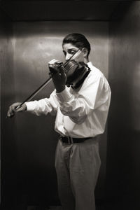 Young man holding camera while standing at home