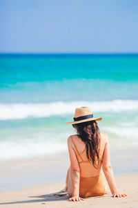 Rear view of woman sitting at beach