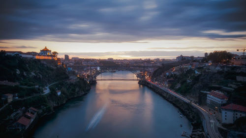 Bridge over river in city against cloudy sky