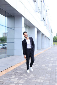 Full length of young man standing on footpath