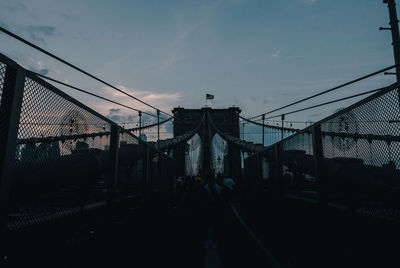 Silhouette people on bridge against sky during sunset