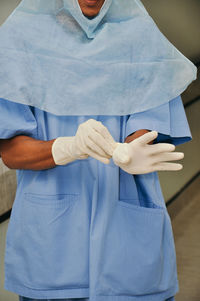 Midsection of surgeon wearing surgical glove in hospital
