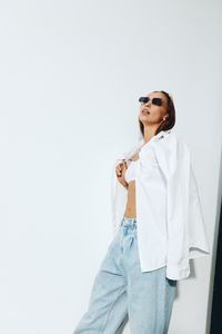 Portrait of young woman standing against white background