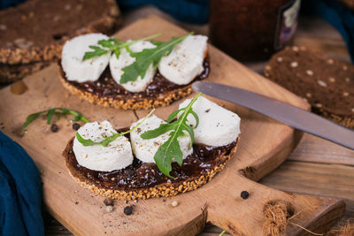Bruschetta with fig jam, goat cheese and rucola on wooden plate. sandwiches with cheese.
