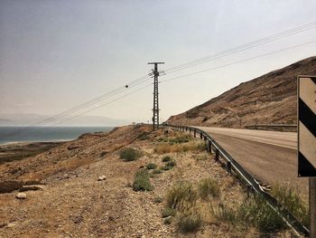 Electricity pylon by road against sky