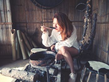 Woman smelling roasted coffee beans while sitting in hut