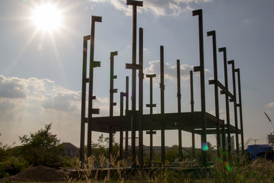 Low angle view of metallic structure on field against sky