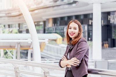 Portrait of smiling young businesswoman standing on elevated walkway 