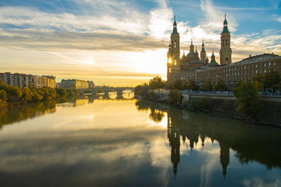 Reflection of building on river during sunset