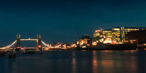 Illuminated bridge over river at night