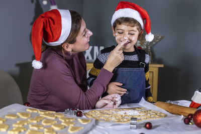 Mother and son playing while preparing cookies at home during christmas
