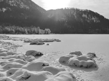 Scenic view on a frozen lake against the sun in the bavarian alps