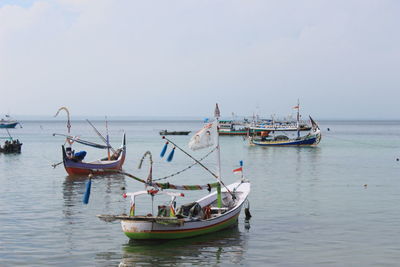 Fishing boats sailing in sea against sky