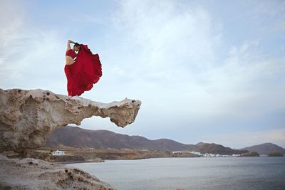 Woman in red dress on rock formation