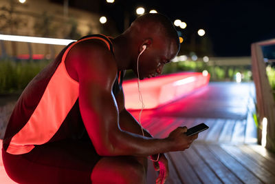 African american athlete browsing smartphone at night