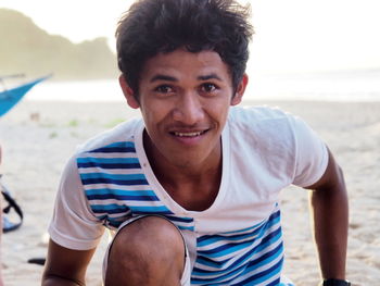 Portrait of smiling young man standing at beach