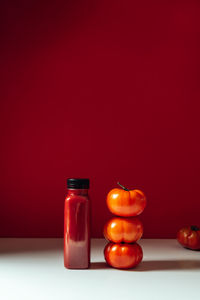 Close-up of lit candles on table against red background